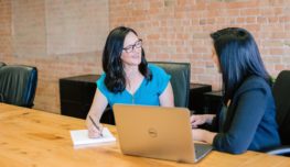 Photo by Amy Hirschi woman in teal t-shirt sitting beside woman in suit jacket